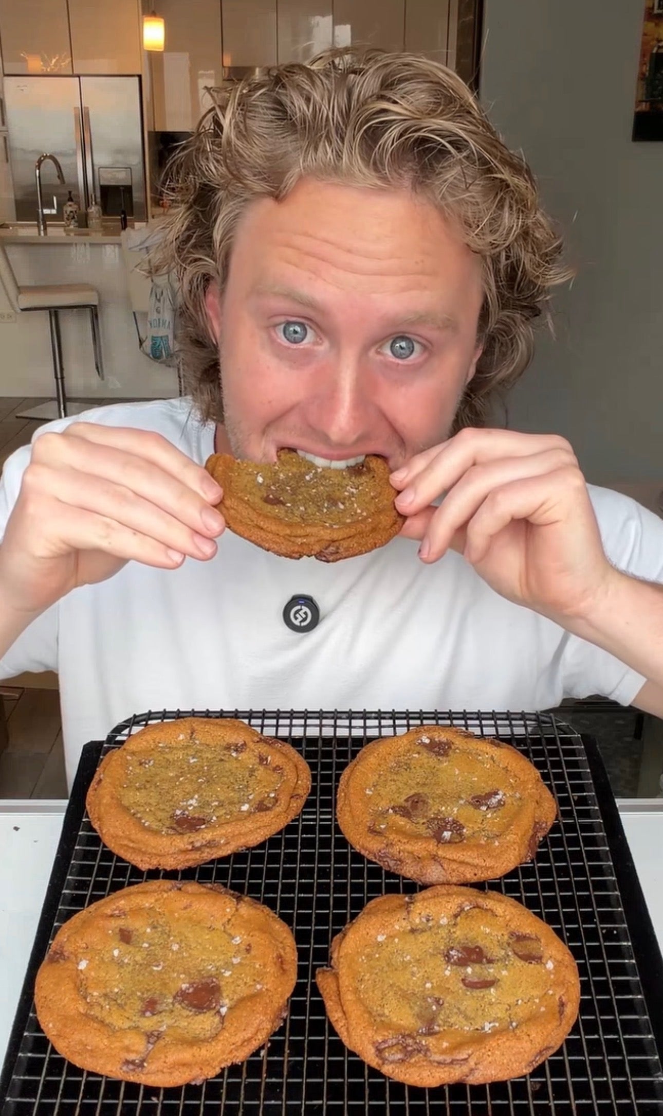 Lukas, founder of Good Ol' Cookie, holding a cookie above a tray of fresh-baked ones